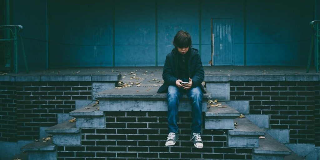 A little boy sitting on stairs and using a phone. Credit: Gaelle Marcel on Unsplash
