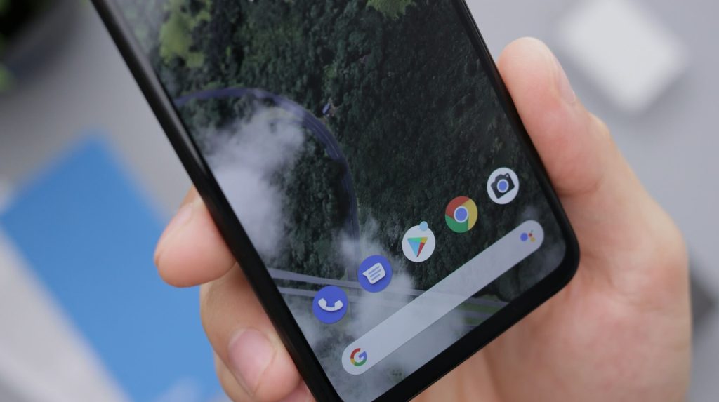 Closeup of person holding a smartphone showing some app icons and a google bar