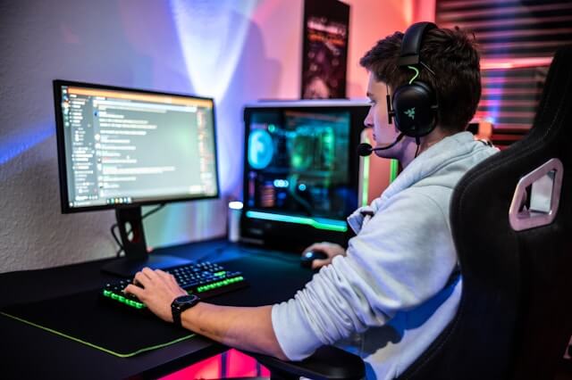 Young man sitting at his PC using Discord with headphones on